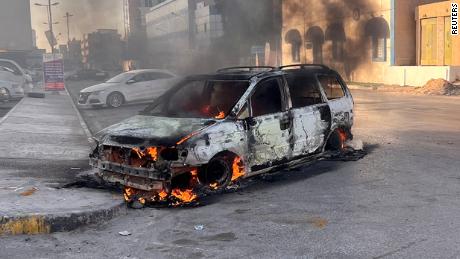 27 Ağustos 2022, Libya, Trablus'taki çatışmalar sırasında sokakta bir araba yanıyor. 