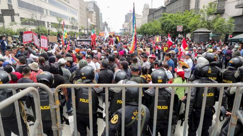 Peru'da Başkan Pedro Castillo'nun 7 Aralık'ta meclisi feshedeceğini açıklamasının ardından, insanlar Peru Kongresi dışında toplanırken polis memurları nöbet tutuyor.