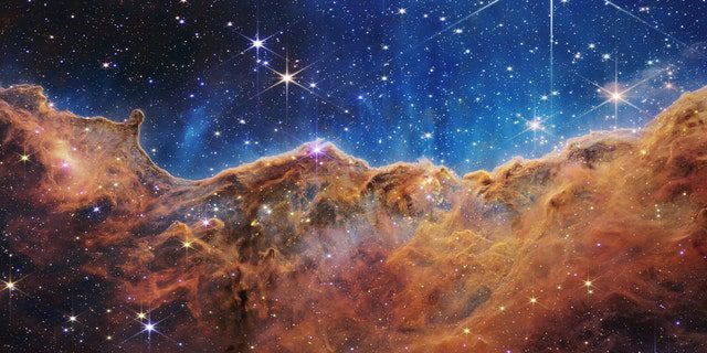 Ay ışığının aydınlattığı bir akşamda kayalık dağlara çok benzeyen şey, aslında Karina Bulutsusu'ndaki yakındaki genç yıldız oluşum bölgesi NGC 3324'ün kenarıdır.  NASA'nın James Webb Uzay Teleskobu üzerindeki Yakın Kızılötesi Kamera (NIRCam) tarafından kızılötesi ışıkta çekilen bu görüntü, yıldız doğumunun önceden gizlenmiş bölgelerini ortaya koyuyor.